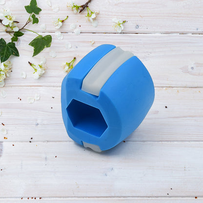 A hand holding the blue Jawline Exerciser, demonstrating its portable size.