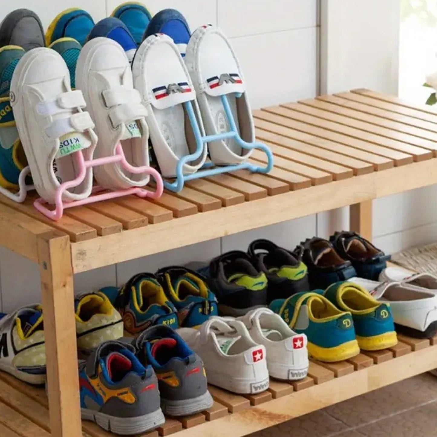 Several pairs of shoes, including white loafers and colorful sneakers, are displayed on a wooden shoe rack, some using the