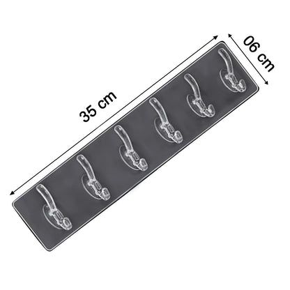 Elegant golden and transparent 6-pin hooks providing storage on a bathroom wall.