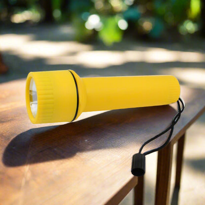 The front end of a yellow plastic torch with a silver reflector is visible on a wooden floor.