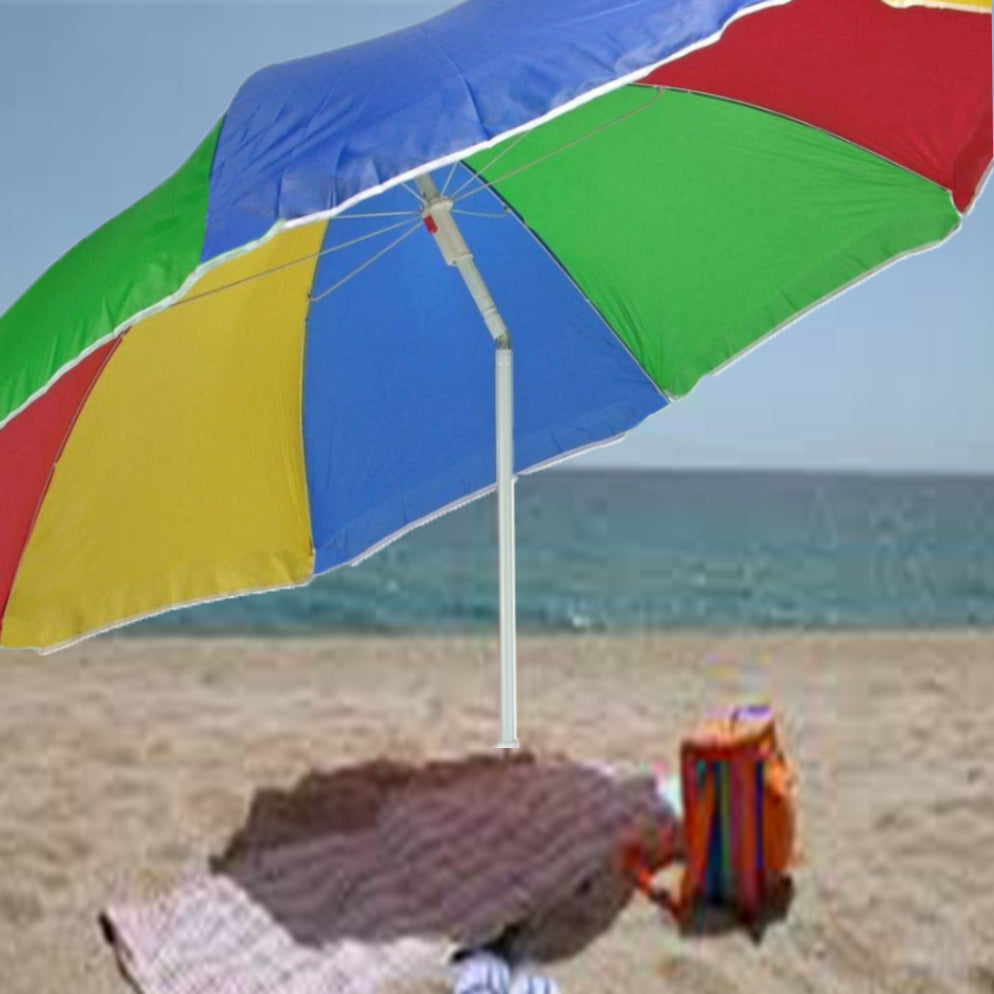 A colorful DrizzlePro umbrella with red, yellow, green, and blue panels stands on a sandy beach with the ocean in the
