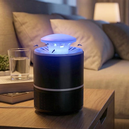 A black and white Mosquito Killer Lamp with a blue light on a wooden nightstand, with a glass of water and a book nearby.